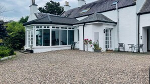 A house with a conservatory, gravel driveway, and outdoor seating area. - 5 Bedrooms, Sleeps 10-12 w/ Wifi, Parking & Garden (Leven)
