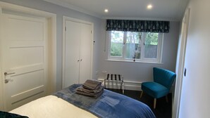 A bedroom with a bed, a chair, a window, and a door. - Thistle Lodge - Quiet Garden Lodge with off road parking (Hemel Hempstead)