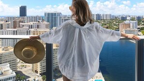 Una persona parada en un balcón, con vista a un paisaje urbano y al agua.