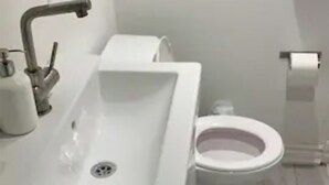 Baño con lavamanos blanco, inodoro y una toalla en el suelo.