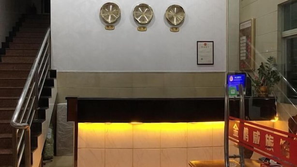 A reception area with a staircase, three wall-mounted clocks, and a framed certificate on the wall. - Jinpengwei Hotel (Shenzhen)