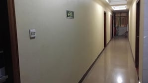 A hallway with a light switch, an emergency exit sign, and a door with a number "2" on the wall. - Jinpengwei Hotel (Shenzhen)