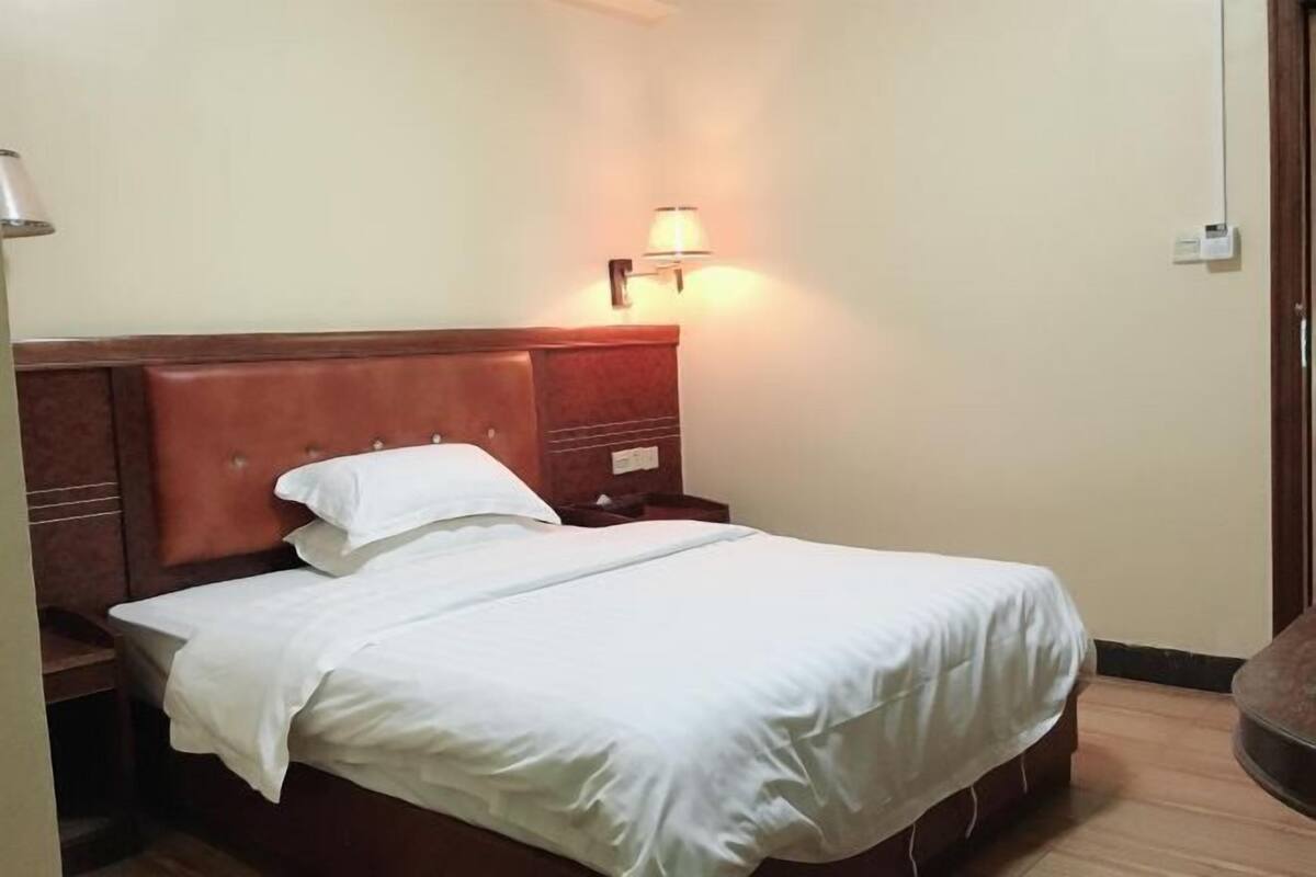 A neatly made bed with white linens in a hotel room.