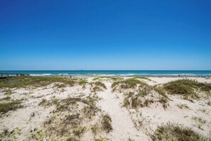 A beach with sand dunes and a clear blue sky.