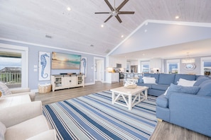 A spacious living area with a large sofa, a coffee table, and a view of the kitchen and dining area.