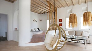 A modern living room with a hanging chair, a glass coffee table, and a sofa. - Villa Super Three (Mykonos)