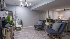 A modern living room with a fireplace, hanging chair, and a dining area with a table and chairs. - Roanoke’s modern Lower Level Apt. (Basement). (Roanoke)