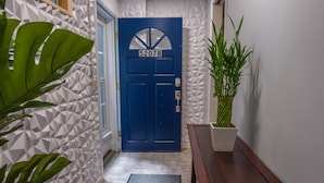A hallway with a blue door labeled 5207B, a wooden bench, and a potted plant. - Roanoke’s modern Lower Level Apt. (Basement). (Roanoke)