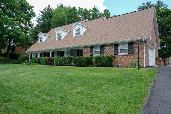 A two-story brick house with a front porch, a covered entryway, and a well-maintained lawn.
