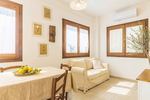 Relax in this serene space with a comfortable sofa, dining table, and artworks on the walls.