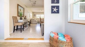 A hallway with a woven basket of towels, a framed seahorse artwork, and a framed starfish artwork on the wall.