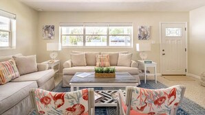 A living room with a sofa, two armchairs, a coffee table, and a door.