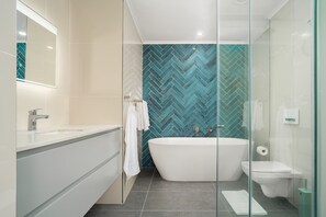 Une salle de bain moderne avec une baignoire sur pieds, une douche à parois de verre et un meuble-lavabo blanc avec un miroir.