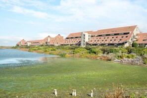 Un hôtel composé de plusieurs bâtiments, situé près d’un lac et entouré de verdure.