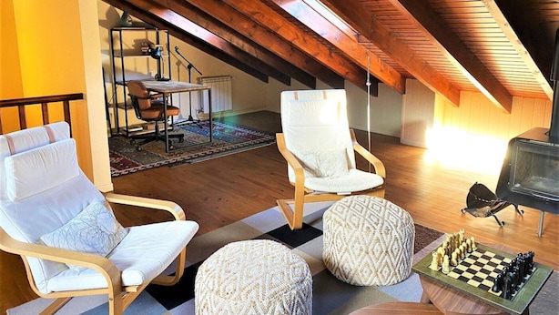 A cozy attic room with wooden beams, a piano, two chairs, ottomans, and a chessboard. - Townhouse 4 rooms Pool, Fireplace, Wi-Fi & Pet-Friendly (Llívia)