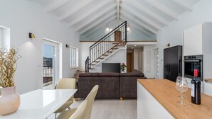 A modern kitchen with a wooden island, a dining area with chairs, a staircase, and a view of the outdoors. - Seaview Villa KING with pool 3km from sea (Omis)