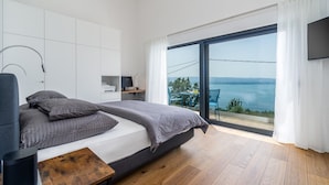 Un dormitorio moderno con una cama grande, un escritorio y vistas al mar.