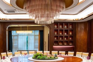 Une salle de conférence équipée d’une table ronde, de chaises, d’un lustre et d’un mur décoratif agrémenté d’étagères.