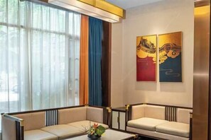 A modern hotel room with a sofa, a coffee table, and two paintings on the wall. - Haoda Jiayuan Hotel (Guangzhou)