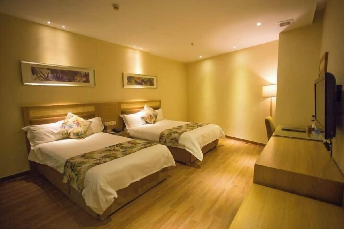Hotellihuone, jossa on kaksi sänkyä, työpöytä ja taideteoksia seinillä.