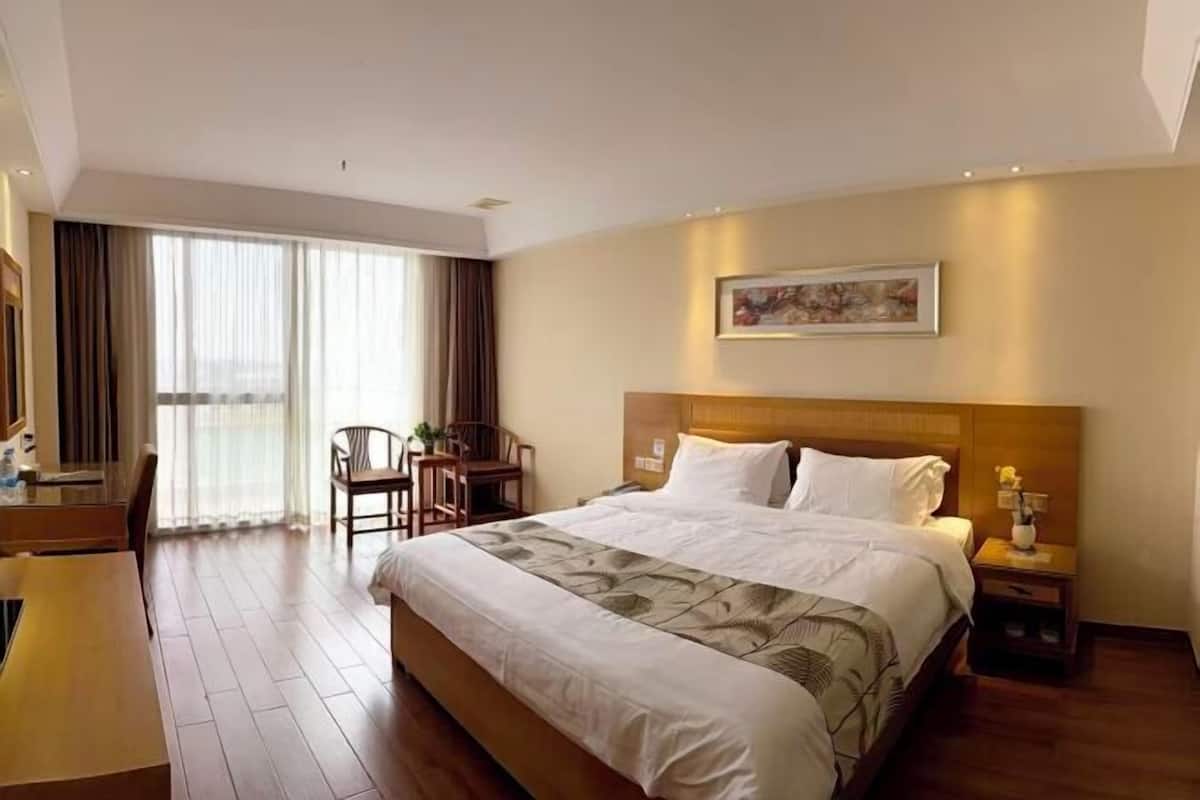 Hotellihuone, jossa on suuri sänky, työpöytä ja tuoli.