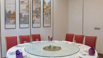 Mesa redonda con cubierta de vidrio rodeada de sillas rojas, puesta con platos, palillos y vasos.