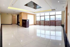 A spacious lobby with a high ceiling, a reception desk, and large windows offering a view. - Haoda Jiayuan Hotel (Guangzhou)