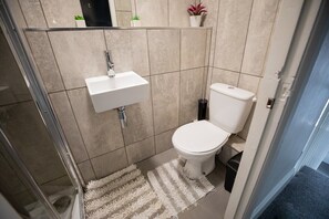 A bathroom with a white sink, toilet, and a shower area.