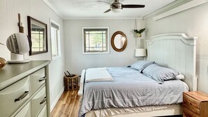 A bedroom with a bed, dresser, ceiling fan, and a window. - Lakeview Cabin- minutes from beach! (Crofton)