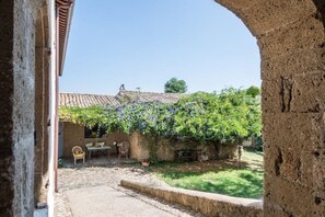 Une cour extérieure avec un mur en pierre, une table et des chaises.