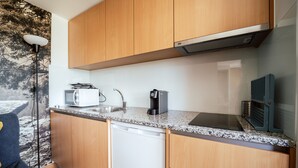 Une cuisine compacte dotée de meubles en bois, d’un four à micro-ondes, d’une machine à café et d’un lave-vaisselle.