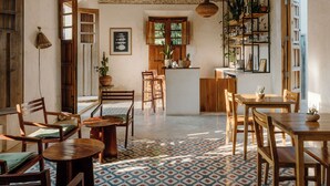 Una habitación amplia con techo alto, vigas de madera, suelo estampado y una zona de cocina central.