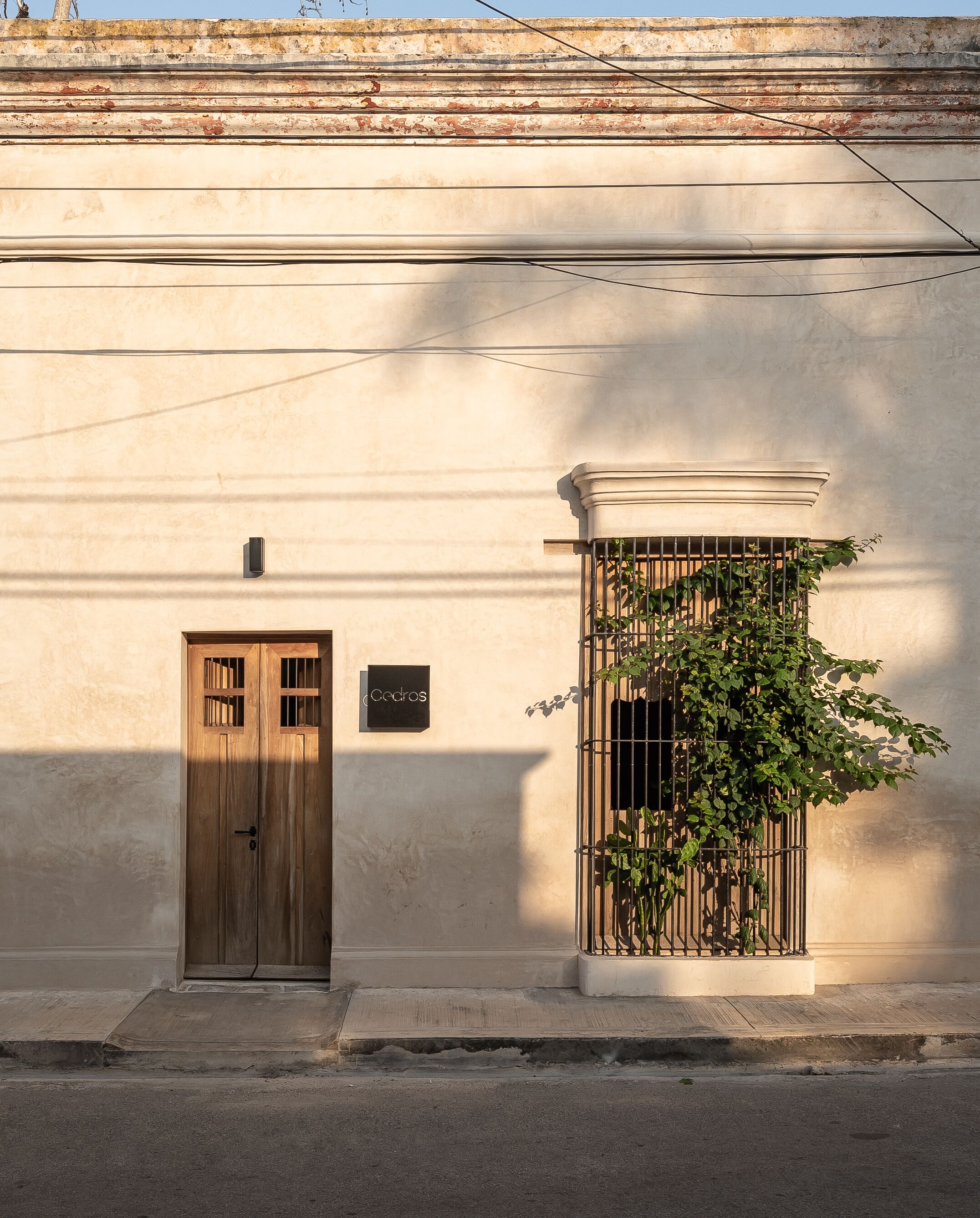 Fachada de edificio con puerta de madera y ventana con reja de metal.