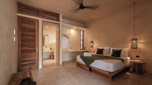 Un dormitorio con una cama grande, cabecera de madera, una mesita de noche pequeña y un ventilador de techo.