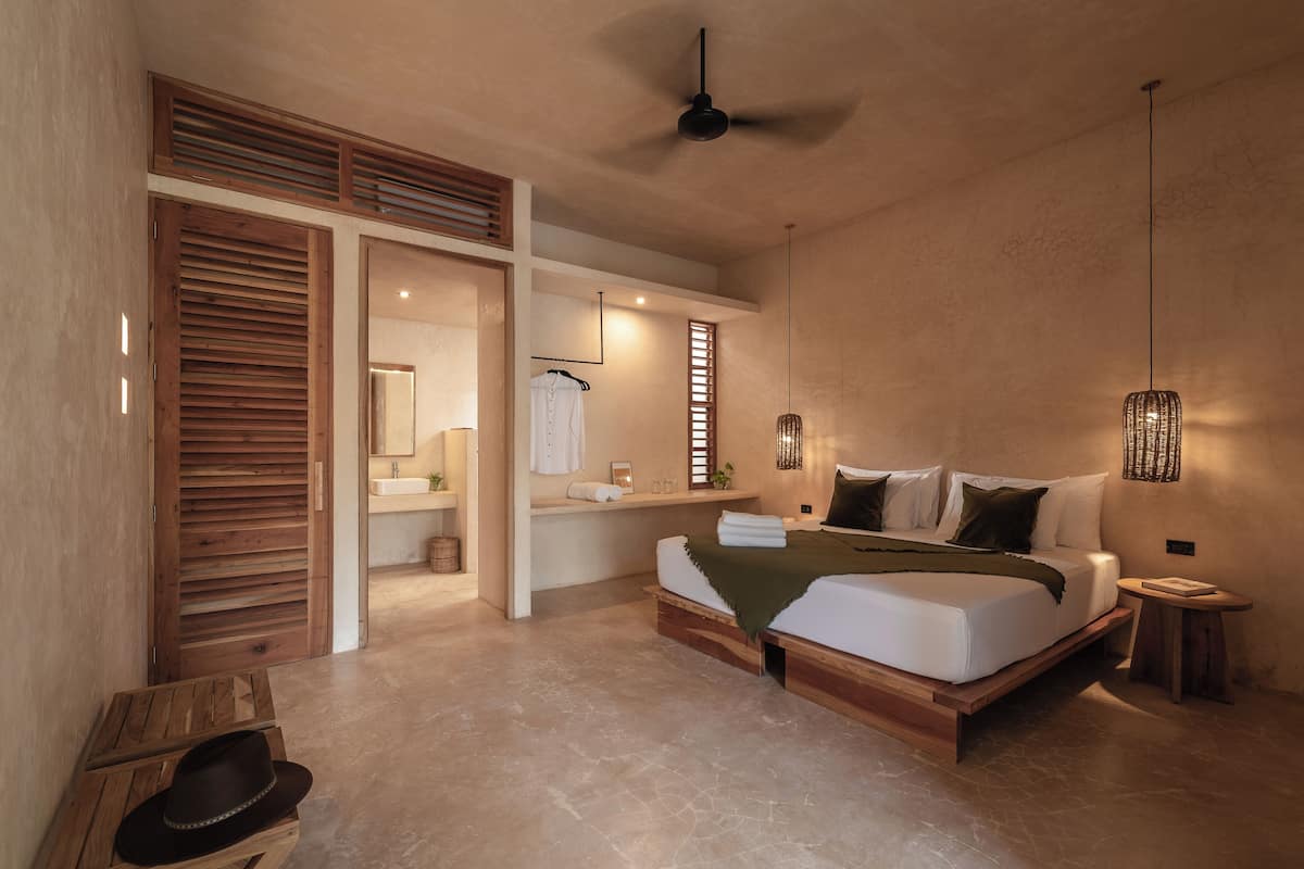 Une chambre à coucher avec un grand lit, une tête de lit en bois, une petite table de chevet et un ventilateur de plafond.