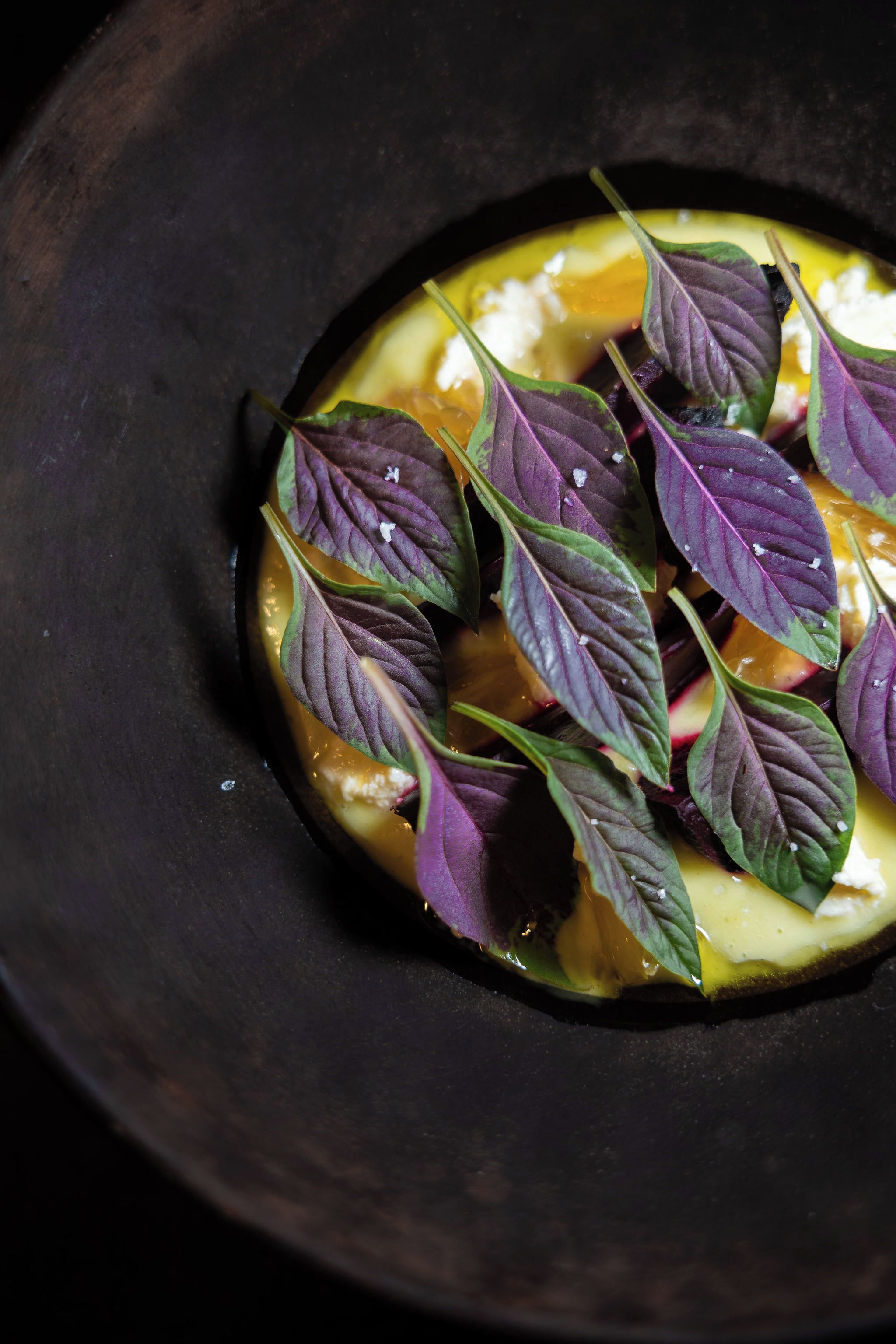 Une vue rapprochée d’un plat agrémenté de feuilles violettes et d’éléments jaunes, qui pourrait être une création culinaire.