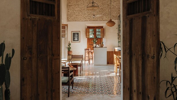 Un interior rústico con puertas de madera, suelo de baldosas y un comedor con sillas y mesa.