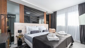 A modern hotel room with a large bed, a bedside table, a desk, and a mirror. - Appartment Val di Bora 2 (Porec)