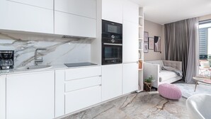 Ett modernt kök med vita köksskåp, en ugn från Bosch och en kaffebryggare.