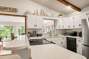 A modern kitchen with white cabinets, a stainless steel refrigerator, and a built-in oven.