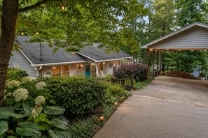 A residential property with a covered porch, a front yard with hydrangeas, and a house with a green door.
