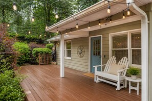 A wooden deck with a white chair and a blue door.