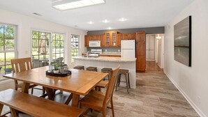 Une cuisine moderne avec des meubles en bois, un îlot central et un coin repas comprenant une table et des chaises en bois.