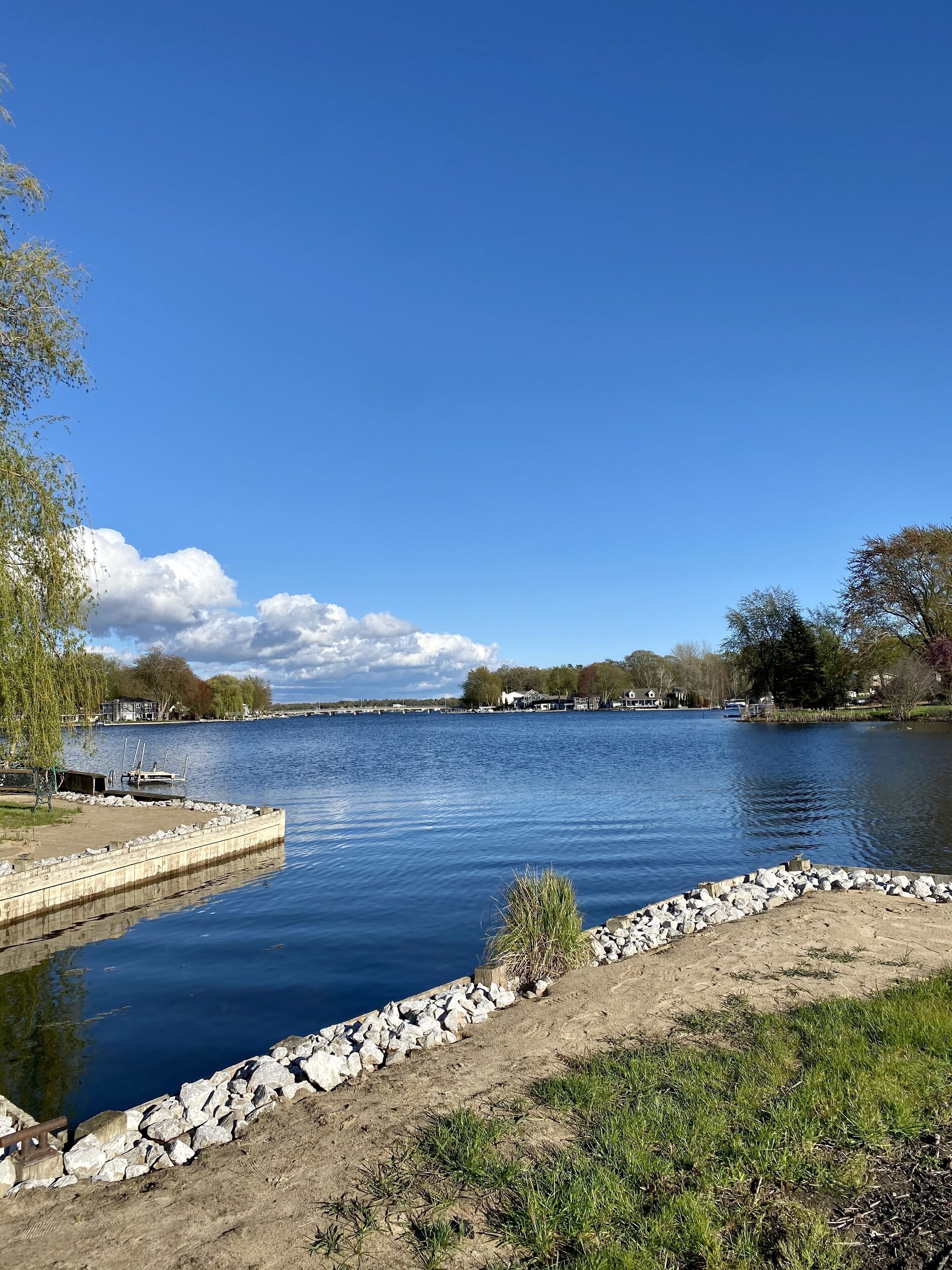 A calm river with a stone embankment and a grassy area.