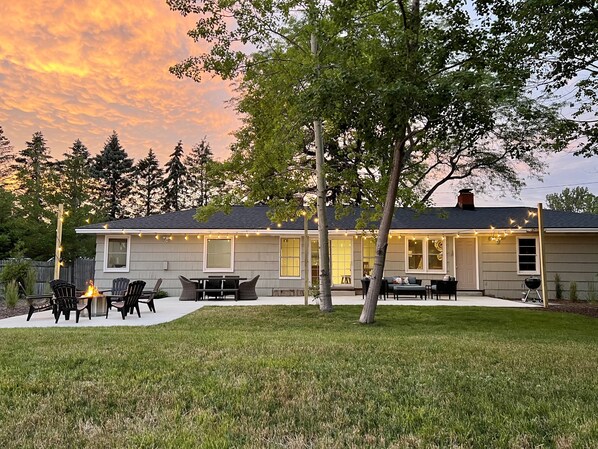 A house with a patio, outdoor seating, and string lights. - Lakefront Home - Hot Tub & Private Beach (Spring Lake)