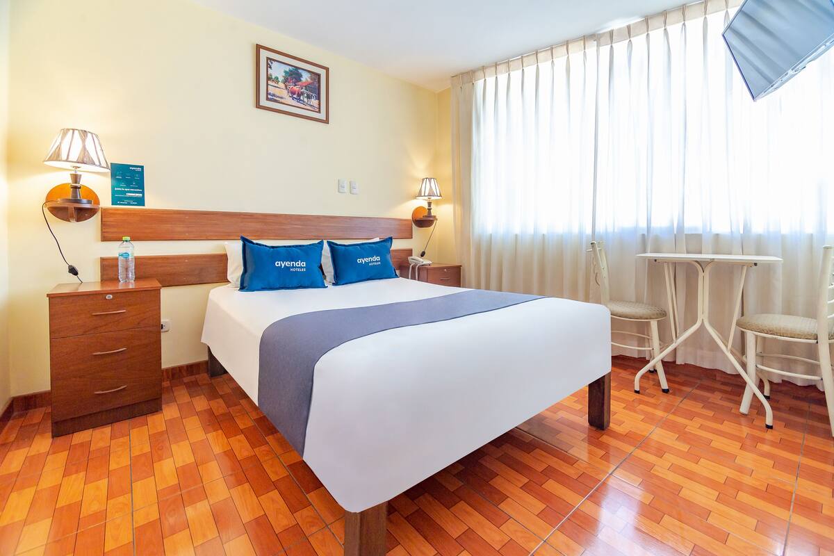 Ein Hotelzimmer mit einem Bett, zwei Nachttischen, einem Schreibtisch und Stühlen.