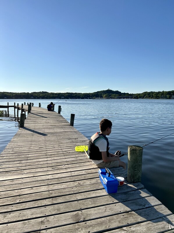 A wooden pier extending into calm water with a person fishing. - New Saugatuck Home: Lake Views & Walk to Town (Douglas)