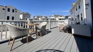 A wooden deck with wicker furniture and a white railing.