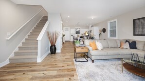 A modern living room with a staircase, a sofa set, and a dining area.