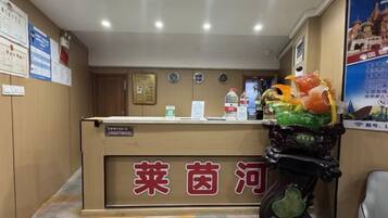 A reception desk with a sign in a foreign language, a clock, and a poster on the wall.